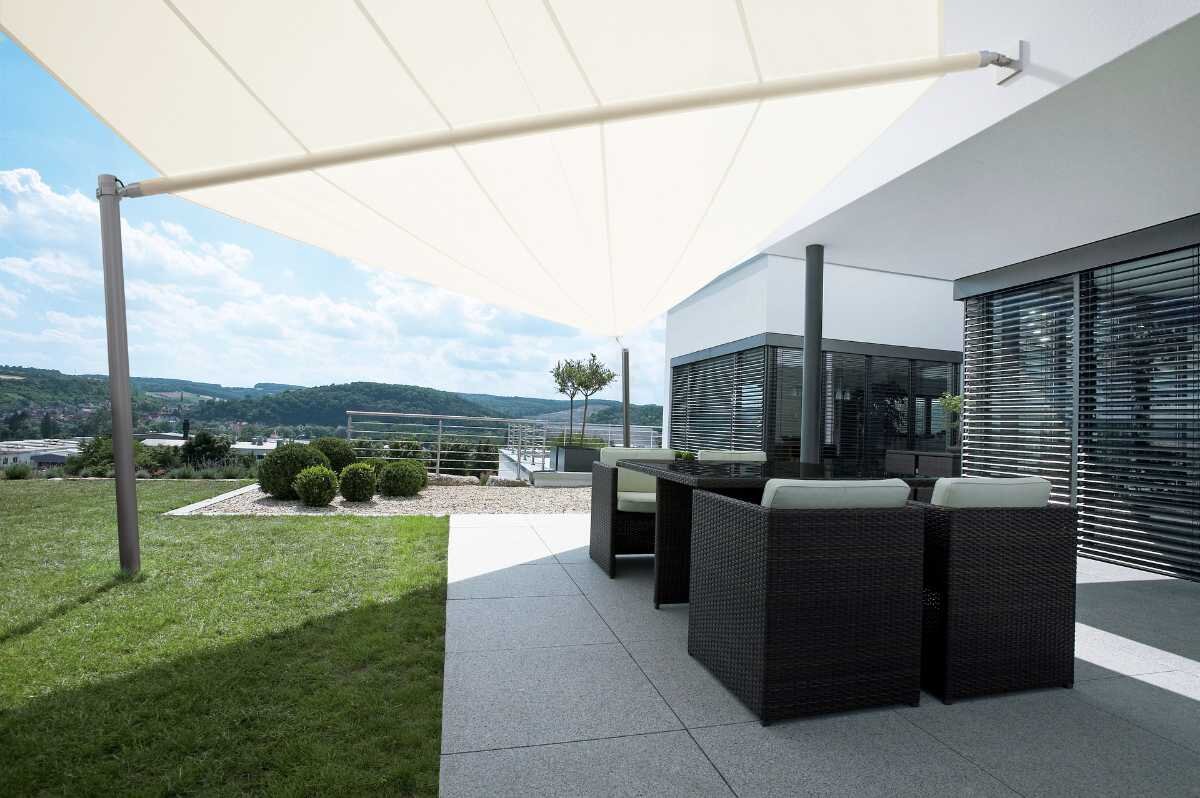 Weißes asymmetrisches Sonnensegel Weißes Sonnensegel über dem Outdoor-Bereich eines Hauses